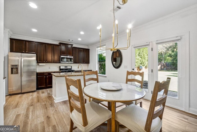 dining space with ornamental molding, sink, and light hardwood / wood-style floors