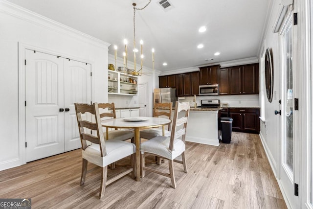 dining room with an inviting chandelier, ornamental molding, and light hardwood / wood-style flooring