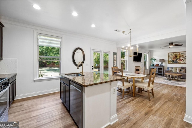 kitchen featuring sink, appliances with stainless steel finishes, light stone countertops, a center island with sink, and decorative light fixtures