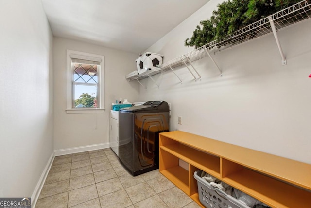 clothes washing area featuring light tile patterned flooring and washer and dryer