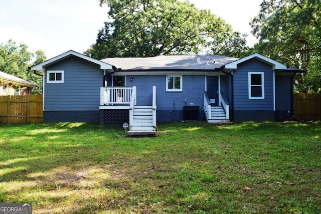 rear view of property with cooling unit, a yard, and a deck