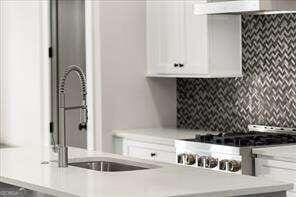 kitchen featuring white cabinetry, extractor fan, and tasteful backsplash