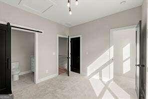 unfurnished bedroom with a barn door and light carpet