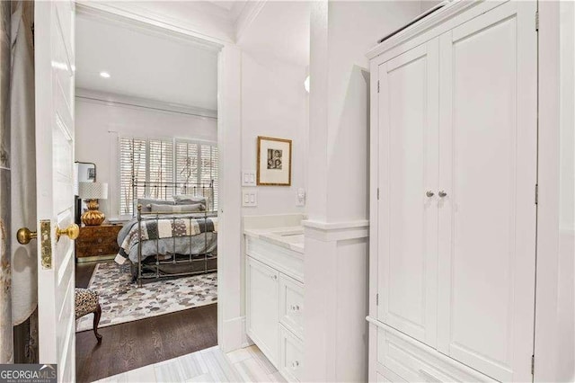 bathroom featuring ornamental molding, hardwood / wood-style floors, and vanity