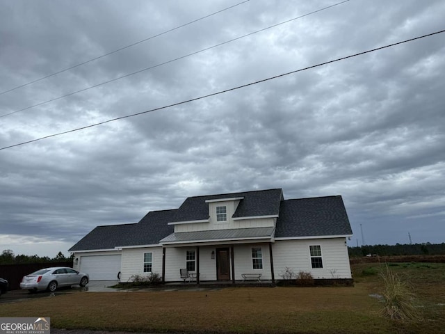 view of front of property featuring a garage, a front yard, and covered porch