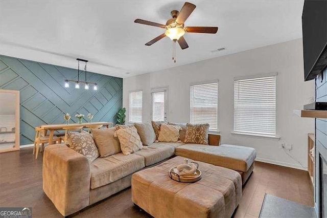 living room with dark wood-type flooring and ceiling fan with notable chandelier