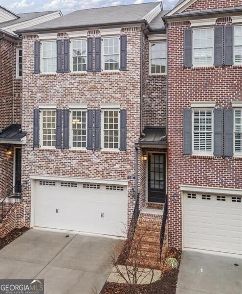 view of property featuring brick siding, driveway, and a garage