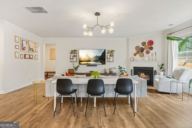 dining area featuring ornamental molding, a chandelier, and light wood-type flooring