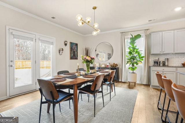 dining room with a notable chandelier, ornamental molding, and light hardwood / wood-style floors