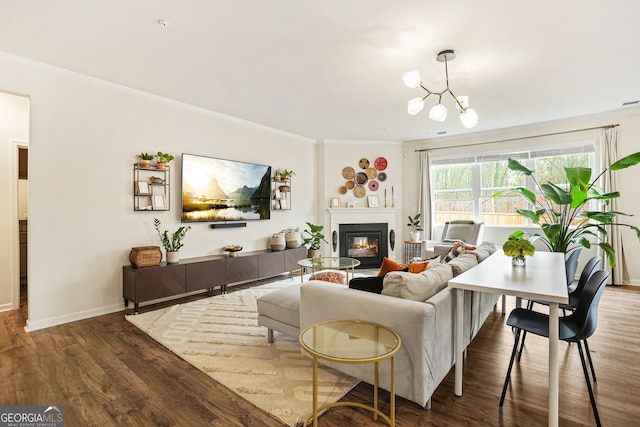 living room featuring dark wood-type flooring, ornamental molding, and a chandelier