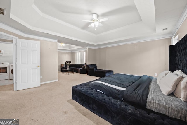 bedroom with crown molding, ceiling fan, independent washer and dryer, a tray ceiling, and light colored carpet