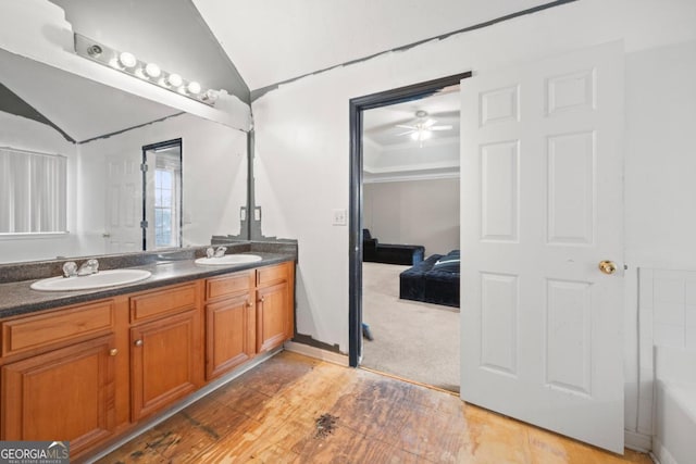 bathroom with crown molding, ceiling fan, hardwood / wood-style floors, vanity, and vaulted ceiling