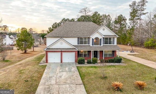 view of front of house featuring a yard, a garage, and covered porch