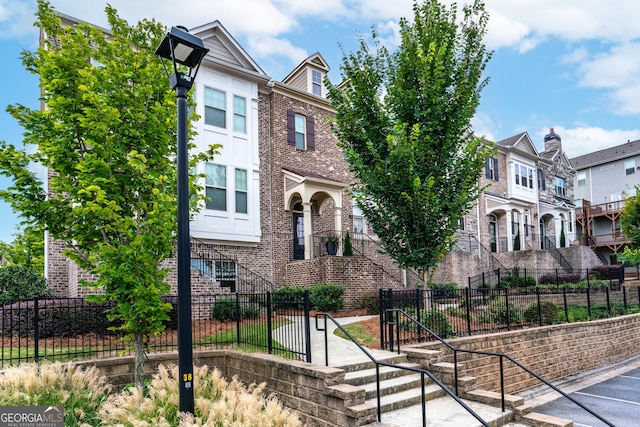 multi unit property with brick siding, a residential view, and a fenced front yard