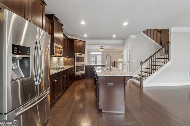 kitchen with stainless steel appliances, a sink, dark wood finished floors, an island with sink, and ornamental molding