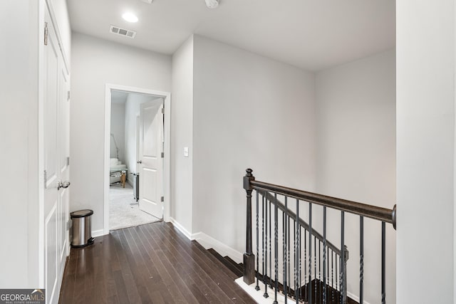 corridor featuring dark wood finished floors, recessed lighting, visible vents, an upstairs landing, and baseboards