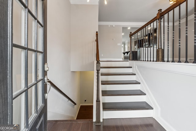staircase featuring a high ceiling, ornamental molding, and wood finished floors