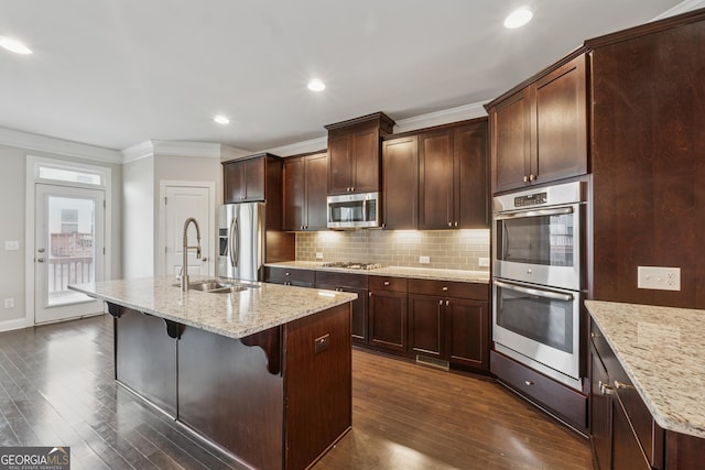 kitchen featuring crown molding, a sink, an island with sink, backsplash, and appliances with stainless steel finishes