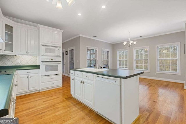 kitchen with sink, white appliances, hanging light fixtures, light hardwood / wood-style floors, and white cabinets