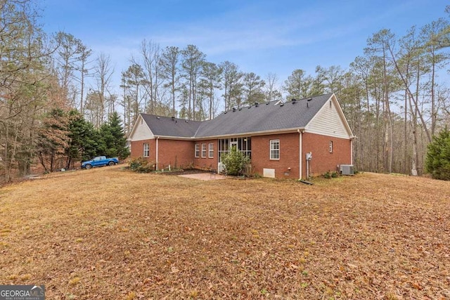 rear view of property with a yard and central air condition unit