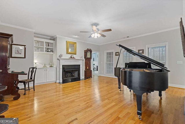 living area with ceiling fan, crown molding, and light wood-type flooring