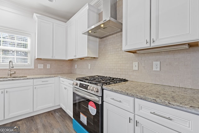 kitchen with stainless steel gas range, white cabinetry, a sink, and wall chimney exhaust hood