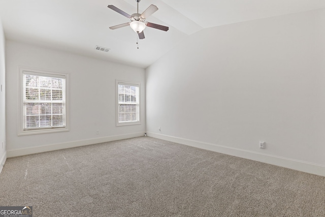 empty room featuring lofted ceiling, light carpet, visible vents, and baseboards