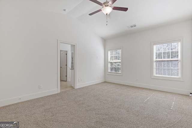 empty room with visible vents, lofted ceiling, a wealth of natural light, and light colored carpet