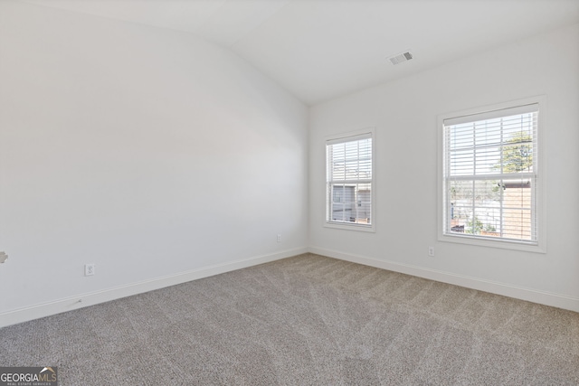 carpeted spare room with lofted ceiling, visible vents, and baseboards