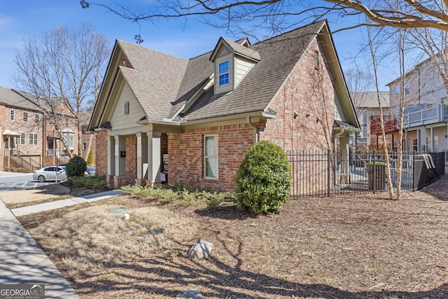 view of side of home featuring a residential view, brick siding, fence, and roof with shingles