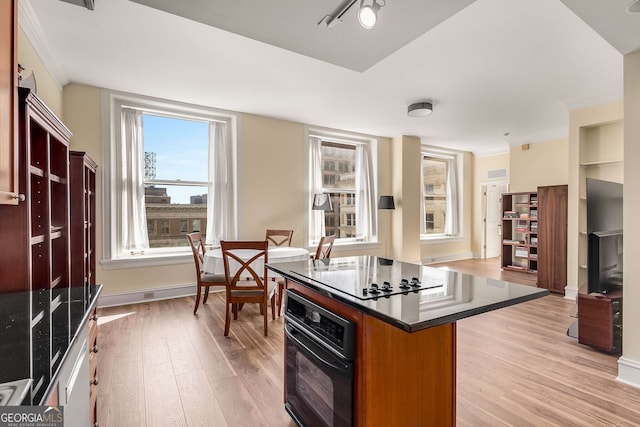 kitchen with crown molding, light hardwood / wood-style flooring, black appliances, and a kitchen island