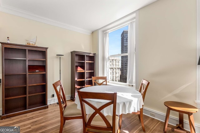 dining room with crown molding and light hardwood / wood-style flooring