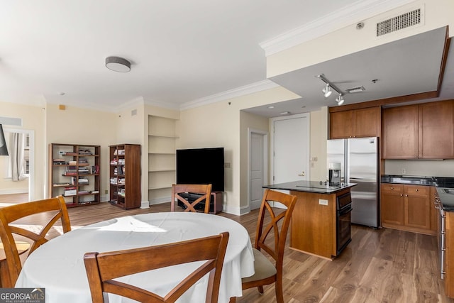 dining area with hardwood / wood-style floors, ornamental molding, and rail lighting