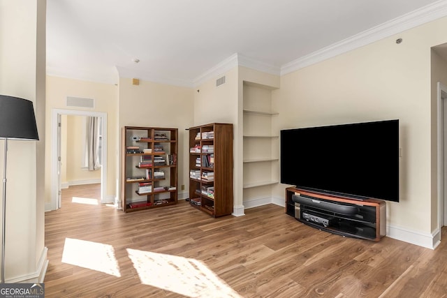 living room featuring crown molding, hardwood / wood-style floors, and built in features