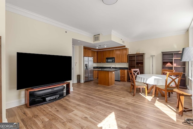 kitchen with stainless steel appliances, crown molding, a kitchen island, and light hardwood / wood-style floors