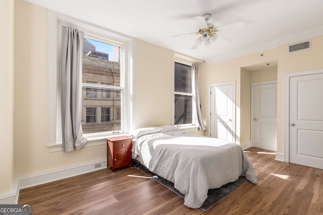 bedroom with ornamental molding, dark hardwood / wood-style floors, and ceiling fan