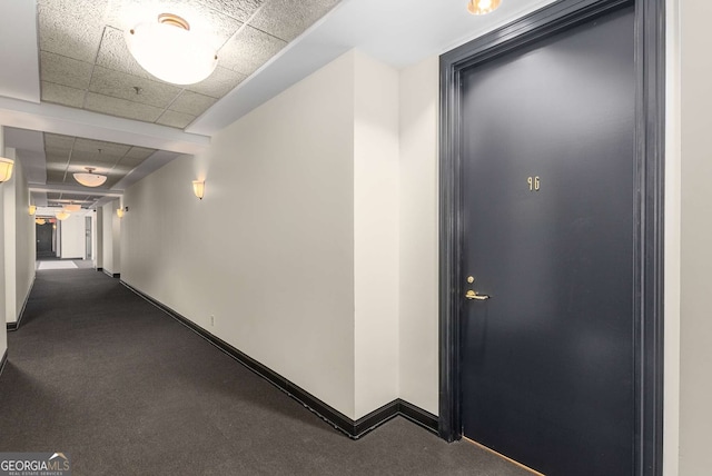 corridor featuring carpet flooring and a paneled ceiling