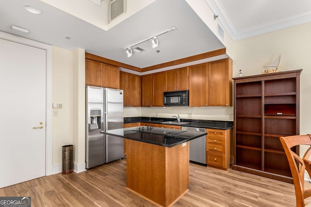 kitchen featuring sink, ornamental molding, a center island, stainless steel appliances, and light wood-type flooring