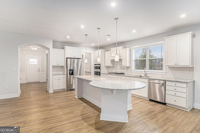 kitchen with a kitchen island, white cabinetry, sink, hanging light fixtures, and stainless steel appliances