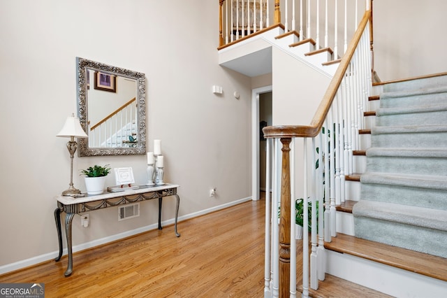 stairway featuring hardwood / wood-style flooring and a towering ceiling