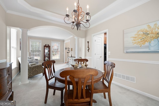 dining space featuring ornamental molding, light carpet, a raised ceiling, a chandelier, and ornate columns