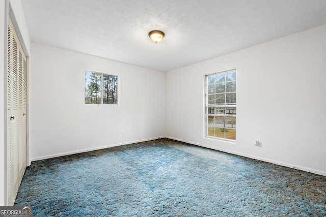 unfurnished bedroom with dark carpet, a closet, and a textured ceiling