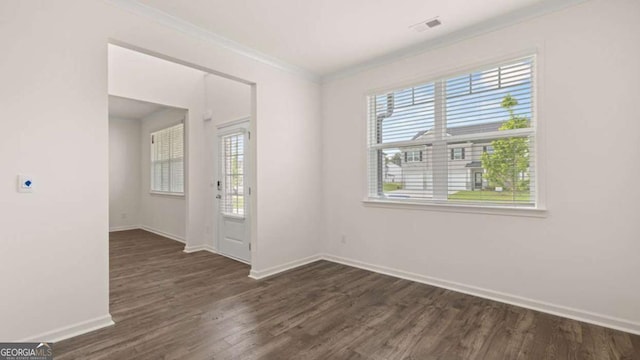 empty room featuring crown molding, plenty of natural light, and dark wood-type flooring