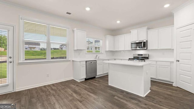 kitchen featuring crown molding, appliances with stainless steel finishes, a kitchen island, and white cabinets