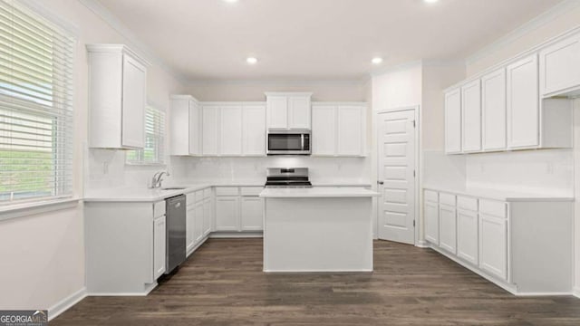 kitchen featuring stainless steel appliances, white cabinetry, a kitchen island, and backsplash