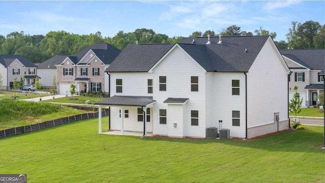 rear view of property featuring cooling unit, a garage, and a yard