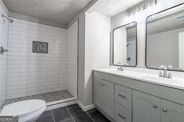 bathroom featuring vanity, tiled shower, toilet, tile patterned floors, and a textured ceiling