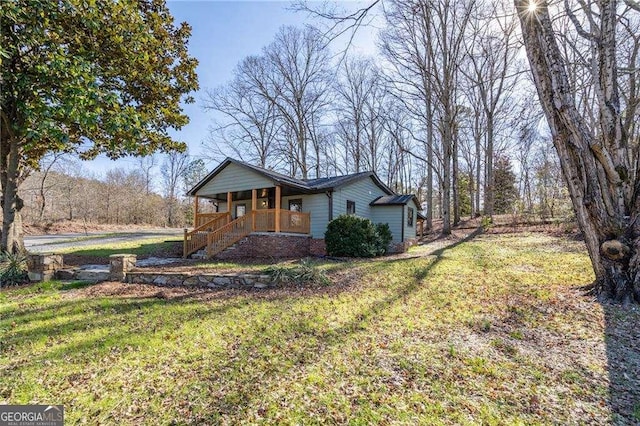 view of side of property with a porch and a lawn