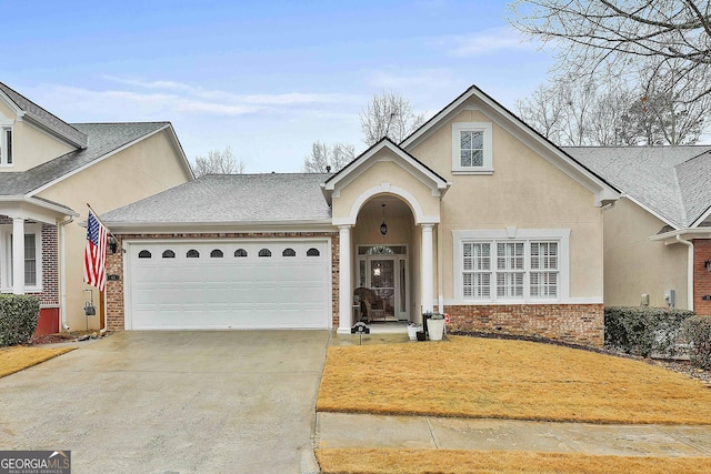 traditional-style house featuring concrete driveway, brick siding, an attached garage, and stucco siding