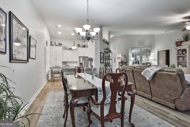 dining area featuring ceiling fan with notable chandelier, vaulted ceiling, and light wood-type flooring